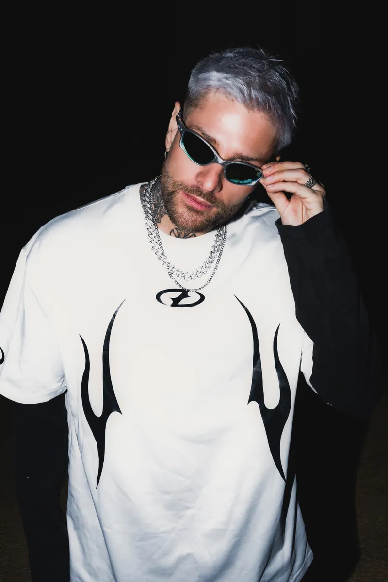 Rafael Cerato adjusting his sunglasses in a white graphic shirt